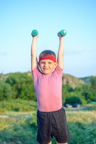 Smiling Strong Boy Raising Two Dumbbells - Foto, afbeelding