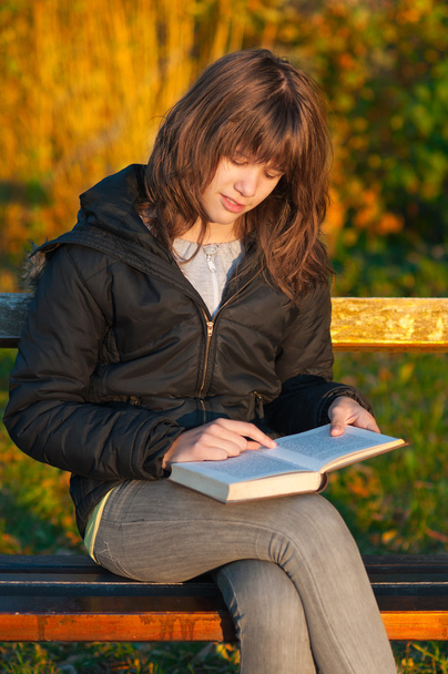 vrij tienermeisje leest het boek in het park op zonnige herfstdag - Foto, afbeelding