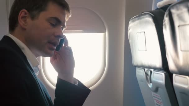 Young man having a business phone talk in plane - Video