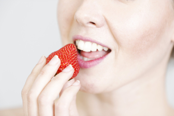 Woman holding up a strawberry - Foto, imagen
