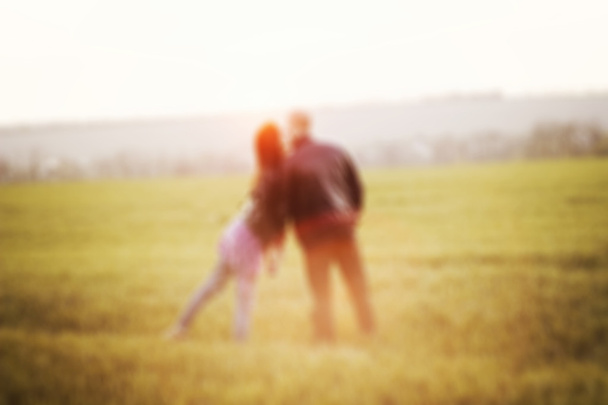 verschwommenes Paar steht und küsst sich im Sonnenuntergang auf dem Feld - Foto, Bild