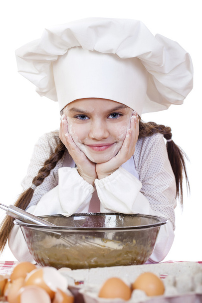Little girl in a white apron and chefs hat knead the dough in th - Foto, Imagem