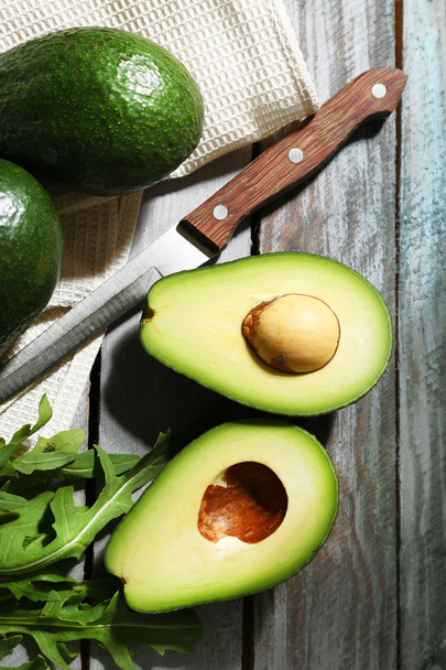 Sliced avocado, arugula on wooden background - Photo, image