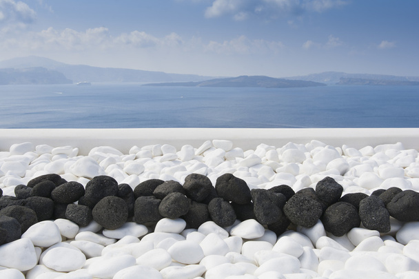 Pedras vulcânicas pretas sobre branco. Detalhe da decoração na ilha de Santorini
 - Foto, Imagem