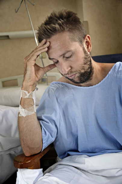 νεαρός άνδρας τραυματίες σε δωμάτιο νοσοκομείου κάθεται μόνος στον πόνο που ανησυχούν για την κατάσταση της υγείας του - Φωτογραφία, εικόνα