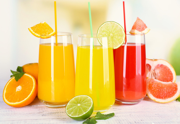 Glasses of different juice with fruits and mint on bright background - Photo, Image