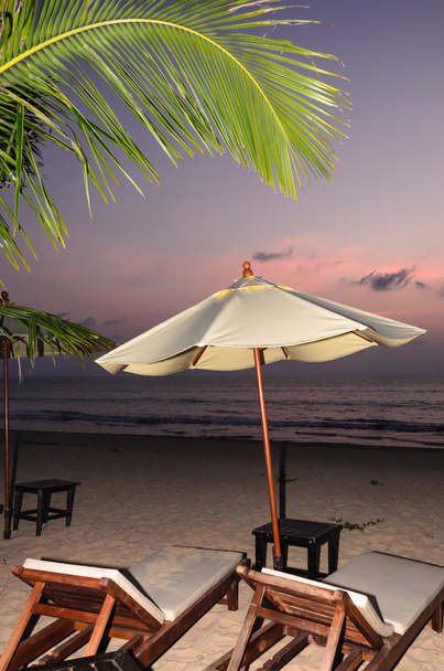 Siluetas de sombrillas de playa puesta de sol y cielo
 - Foto, Imagen