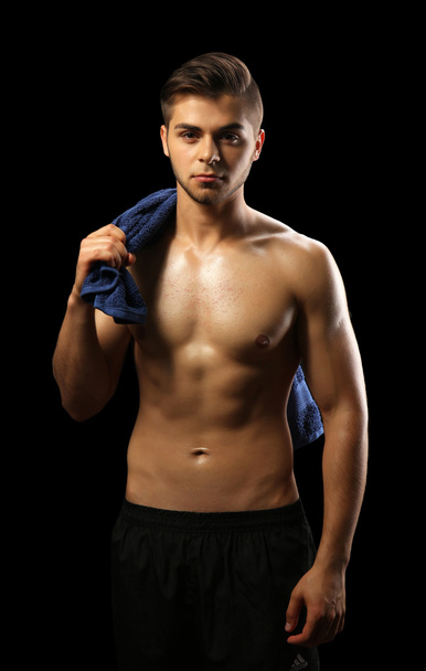 Muscle young man holding towel on dark background - Фото, изображение