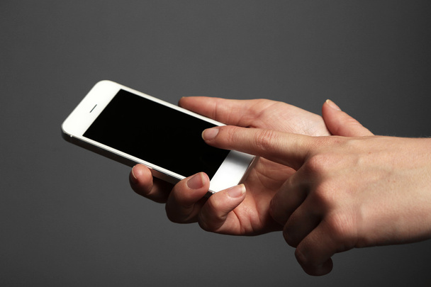 Hands holding mobile smart phone on gray background - Foto, imagen