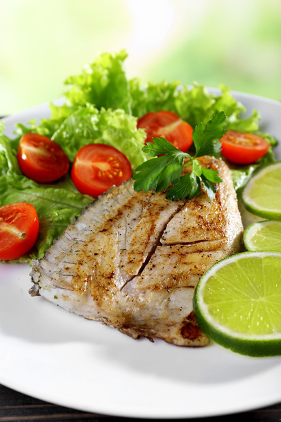 Dish of fish fillet with salad and lime on bright background - Photo, Image