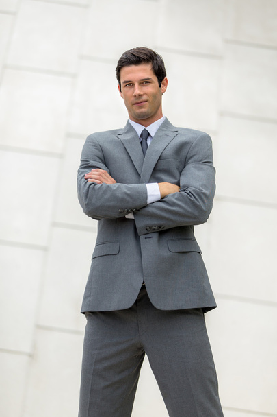 Vertical shot of confident business man young adult folded arms in powerful standing pose - Zdjęcie, obraz