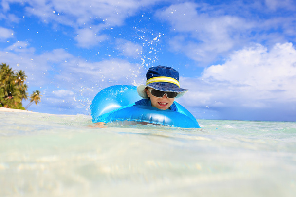 Kleiner Junge mit Rettungsring hat Spaß am tropischen Strand - Foto, Bild