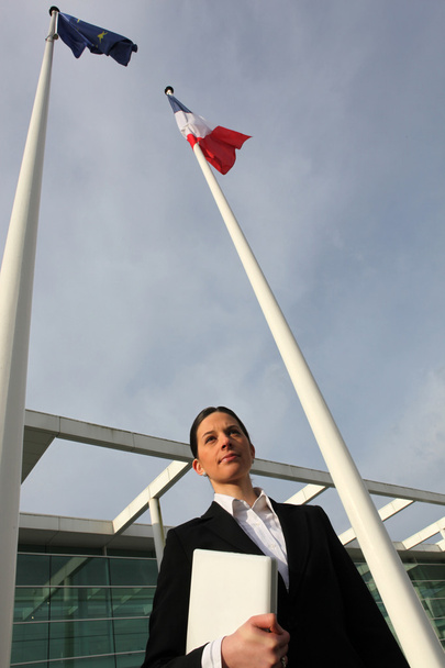 Woman standing next to French and European flagpoles - Φωτογραφία, εικόνα
