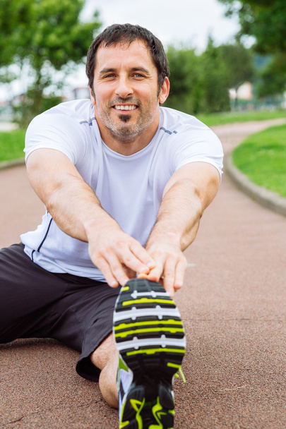 Happy man doing stretching exercises outdoors - Foto, imagen