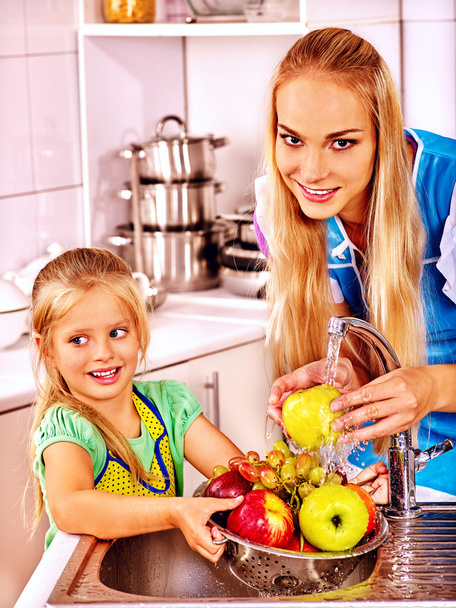 Äiti lapsi pestä hedelmiä keittiössä
. - Valokuva, kuva