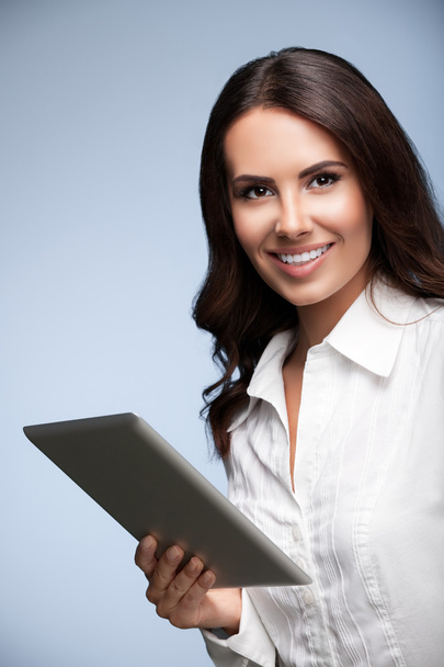 beautiful young businesswoman using no-name tablet pc, over grey - Fotó, kép