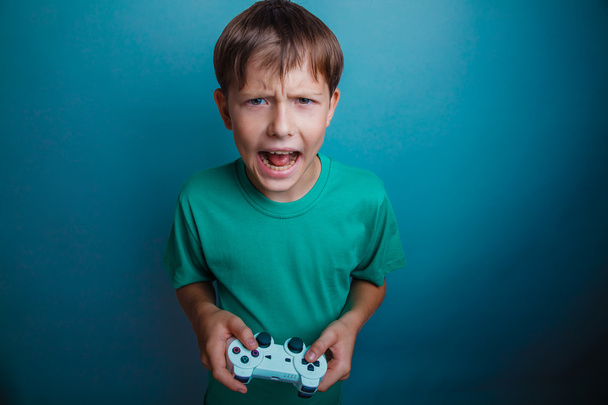 Adolescente chico gritando boca abierta sostiene emociones juego joystick en un
  - Foto, Imagen