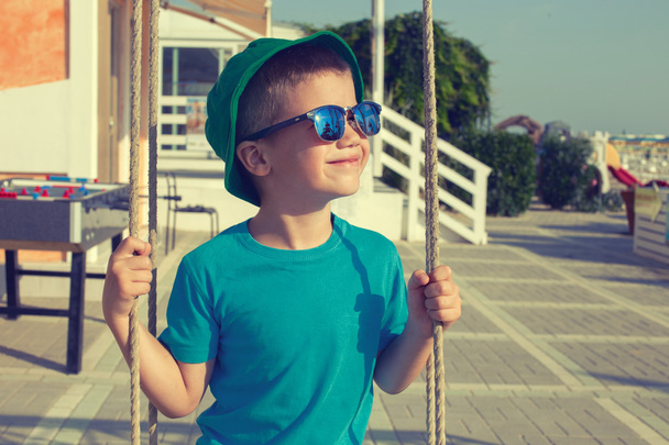 Kleine jongen swingende buiten op zomer dag vintage stijl - Foto, afbeelding