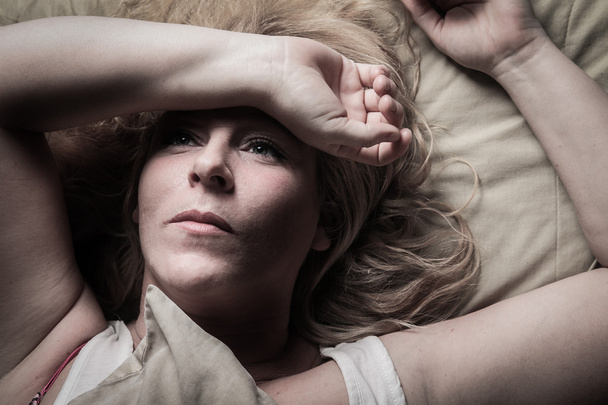 A woman feel sick lying down on bed - Valokuva, kuva