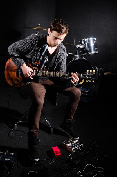 man gitaarspelen in donkere kamer - Foto, afbeelding