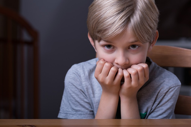 Frightened kid sitting at table - Фото, зображення