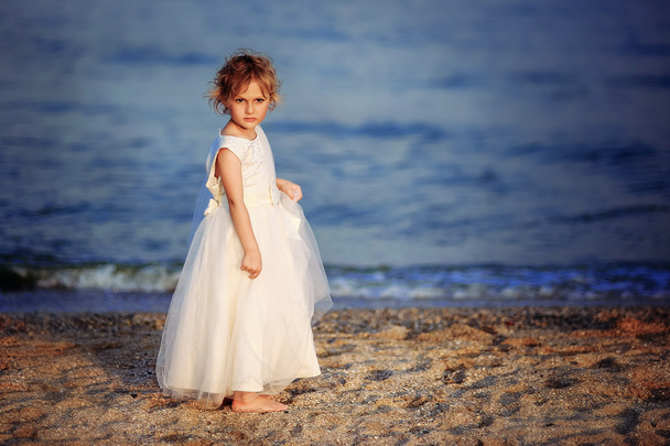 girl in a white dress walks on the sea beach - Foto, Imagem