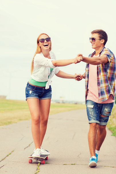 smiling couple with skateboard outdoors - Photo, image