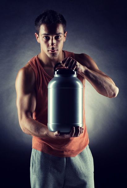 young male bodybuilder holding jar with protein - Photo, Image