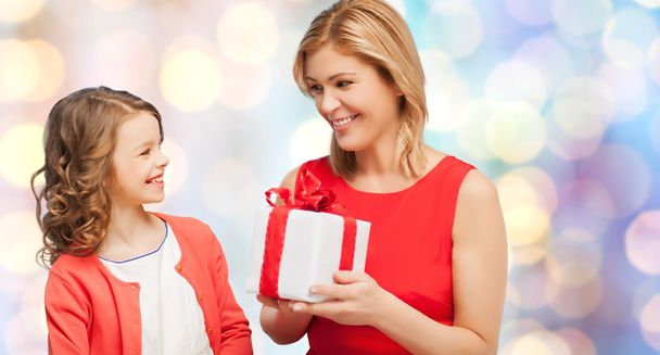 smiling mother and daughter with gift box - Фото, изображение
