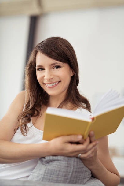 Smiling Pretty Woman on a Sofa Holding a Book - Photo, Image