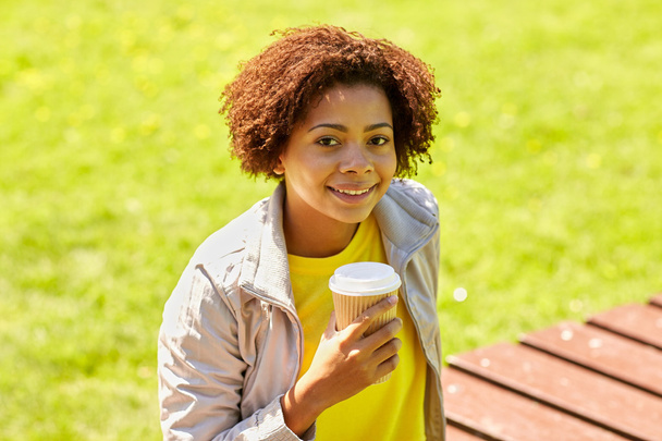 smiling african woman drinking coffee outdoors  - Фото, зображення