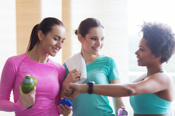 happy women showing time on wrist watch in gym - Foto, imagen