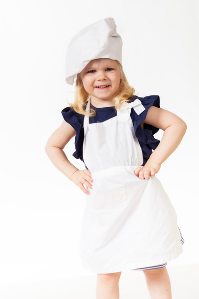 Cute little girl wearing white apron and cap cook - Foto, afbeelding