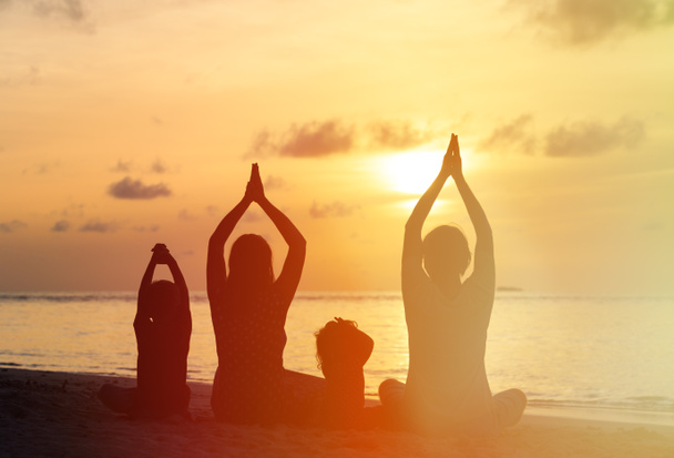 family silhouettes doing yoga at sunset - Photo, Image