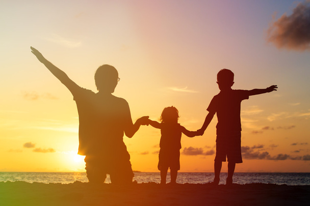 Vater mit zwei Kindern am Strand bei Sonnenuntergang - Foto, Bild