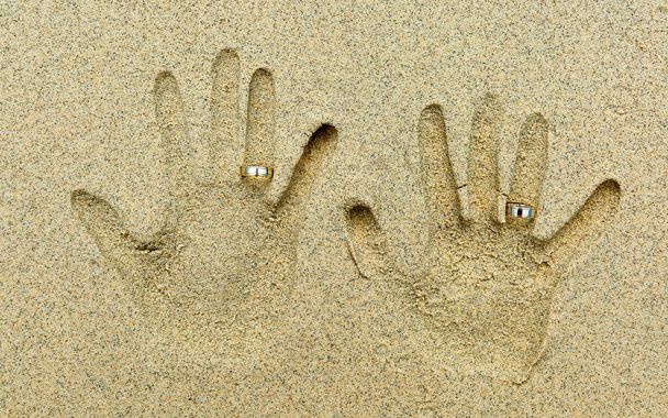 два обручальных кольца на пальцах в песок
 - Фото, изображение
