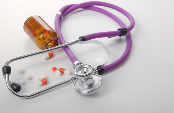 Pillerit, tabletit ja stetoskooppi valkoisella taustalla
 - Valokuva, kuva