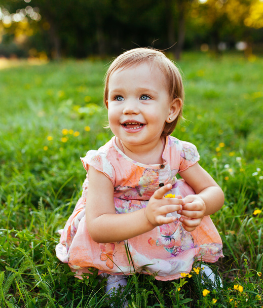 Little girl sitting on the grass. - Фото, зображення