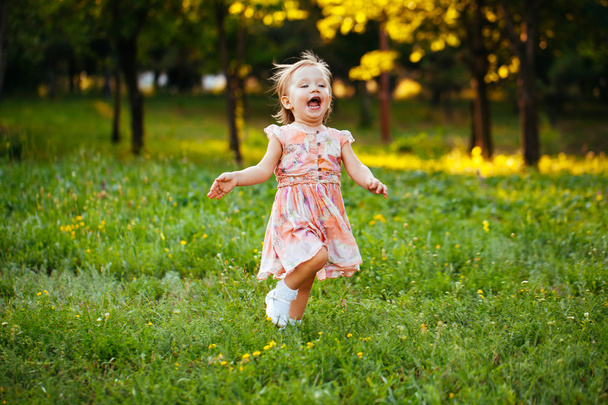 Happy cute little girl running on the grass in the park. Happine - Фото, зображення