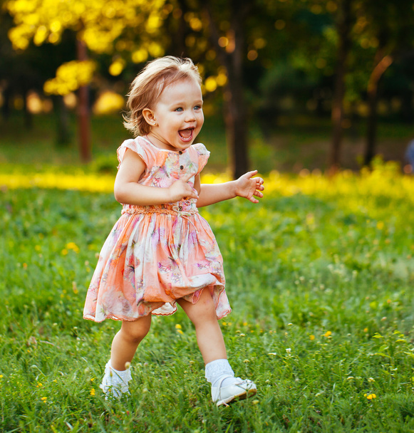 Счастливая маленькая девочка бегает по траве в парке. Хаппин
 - Фото, изображение