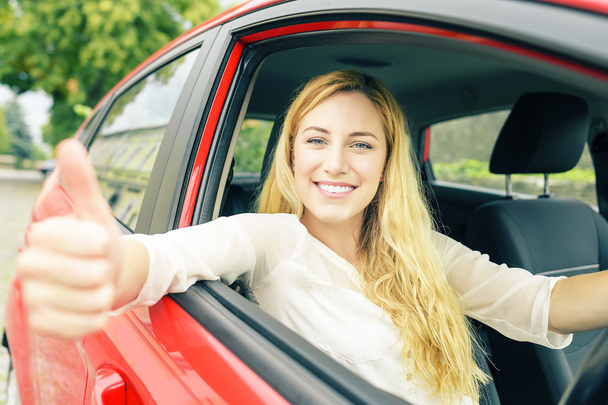 Szczęśliwy uśmiechający się dziewczyna w czerwonym samochodem.  - Zdjęcie, obraz