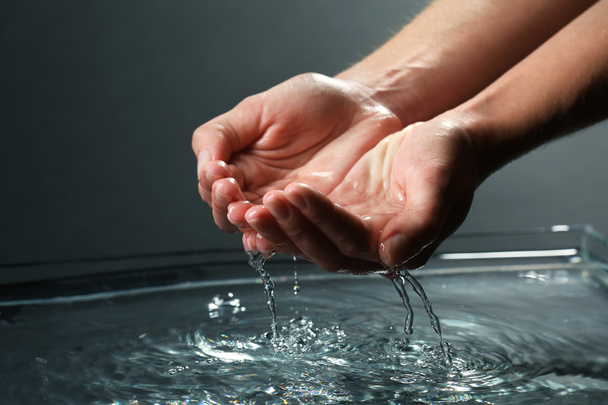 Female hands with water splashing on dark background - Fotó, kép