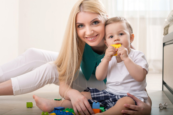 Cheerful young mom is playing with her baby - Photo, image