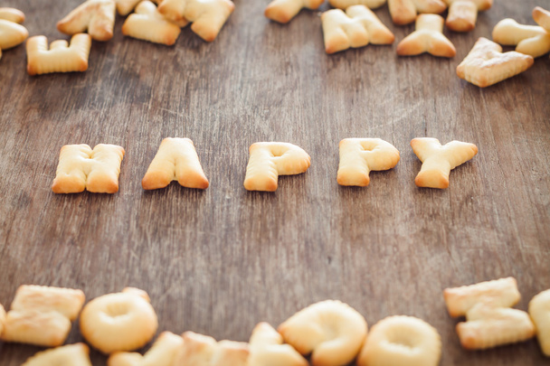 Happy alphabet biscuit on wooden table - Foto, afbeelding