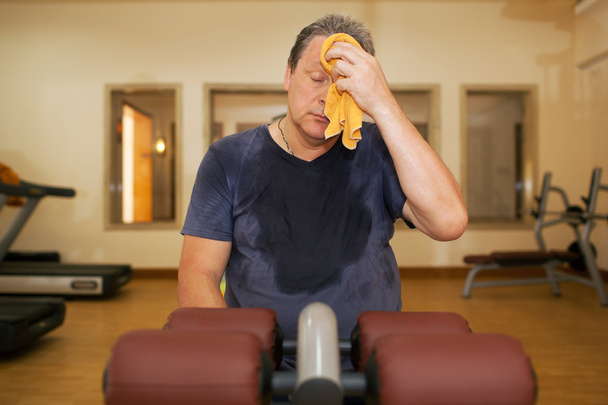 Müder Mann wischt sich Schweiß nach dem Training ab - Foto, Bild