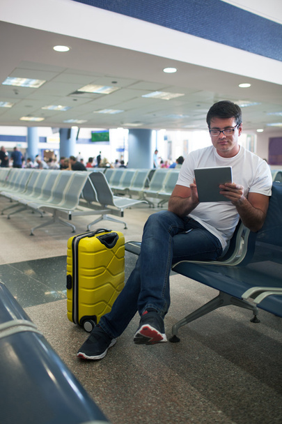 Nuori mies käyttää kosketuslevyä lentokentän loungessa
 - Valokuva, kuva