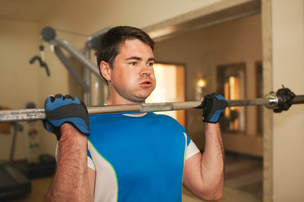 Strong young man exercising with barbell - Photo, Image