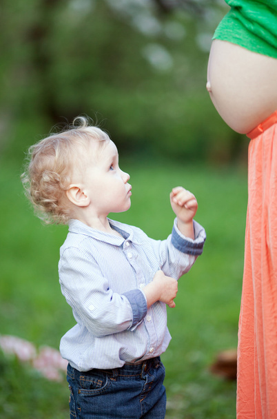 Cute little boy looking at pregnant moms belly - Photo, Image
