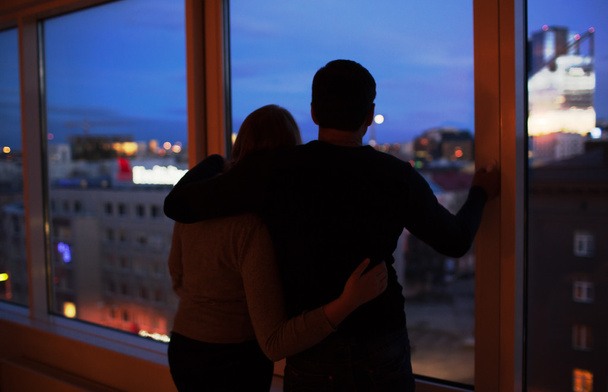 Couple embracing and looking at evening city together - Fotó, kép