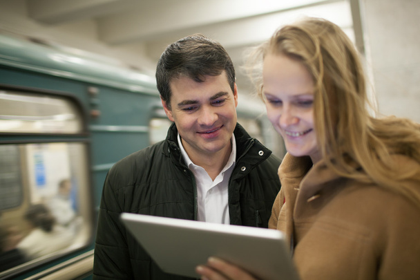 Счастливые молодые люди с тачпадом в метро
 - Фото, изображение